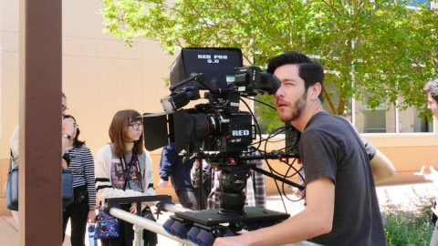Student with camera outdoors in film class